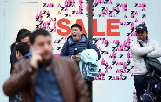 A shopper yawning while waiting outside a shop, during the Boxing Day sales, on Oxford Street, in London, Wednesday, Dec. 26, 2018. (Isabel Infantes/PA via AP)
