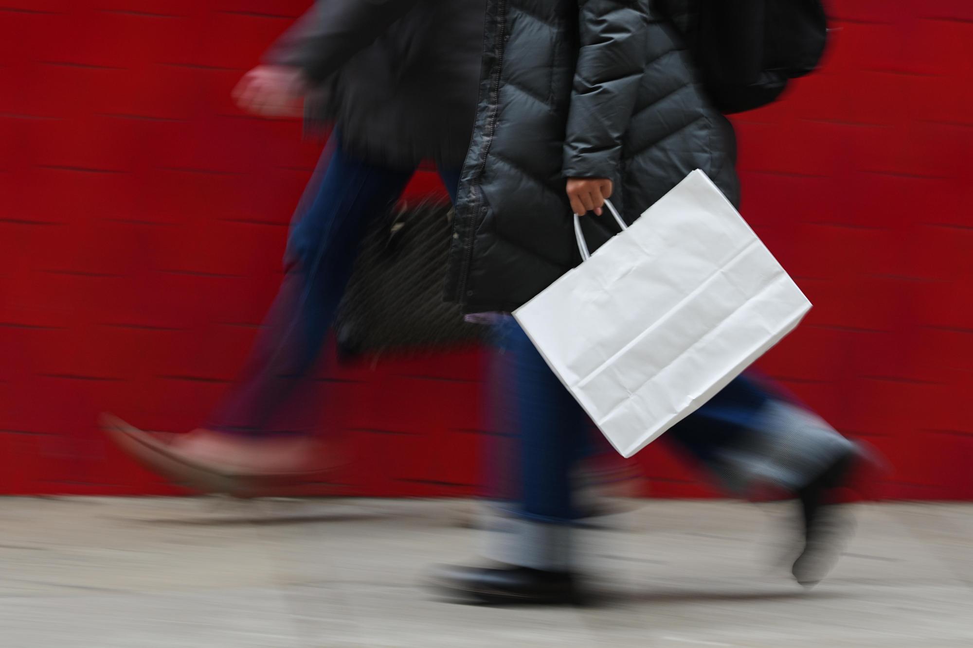 FILE – A person carries a shopping bag in Philadelphia, Dec. 10, 2025. (AP Photo/Matt Rourke, File)
