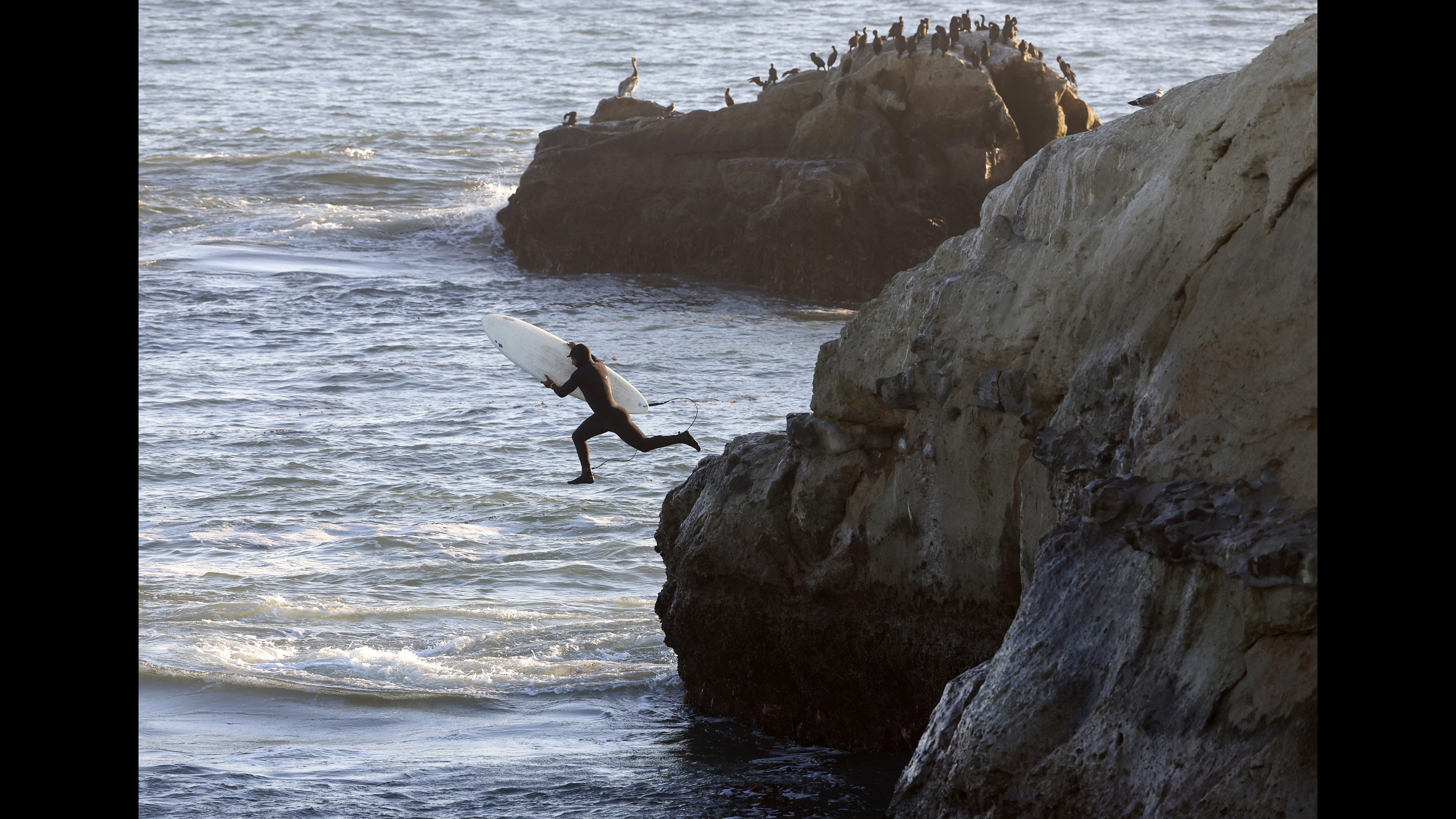 Surfer Ricardo Urbina, from Aptos, heads into the water with...